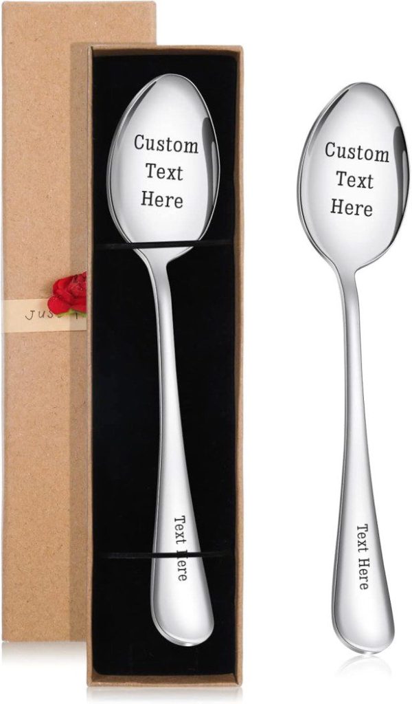 Dos cucharas de plata grabadas con "Texto personalizado aquí", presentadas elegantemente en una caja y de forma individual, lo que las convierte en ideas perfectas para regalos de bautizo.