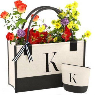 Un bolso beige adornado con una "K" y flores de colores, acompañado de una bolsita a juego, es una idea encantadora para regalar en un bautizo.