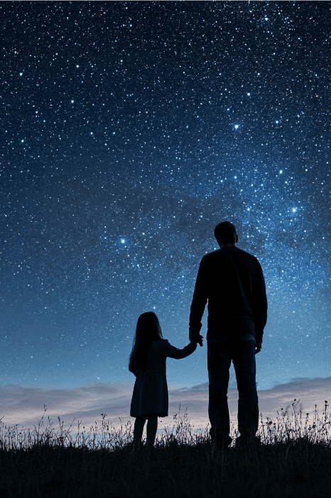 Silueta de un hombre y un niño cogidos de la mano, contemplando un cielo nocturno estrellado, encarnando la esencia de los poemas del Día del Padre para momentos de iglesia.
