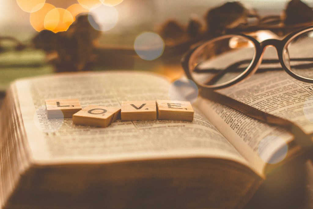 LOVE scrabble tiles and glasses lying on an open Bible, studying unconditional love