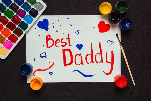 Tintas e papéis coloridos com "Best Daddy" (Melhor Papai) escrito em cores vibrantes, cercado por corações e pinceladas - perfeito para uma lição bíblica criativa no Dia dos Pais.