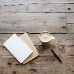 Consecration in the Bible - What Is It? A notebook, pen, and a latte with heart art rest on a rustic wooden table, creating a serene setting ideal for reflection—perhaps contemplating themes of consecration in the Bible.