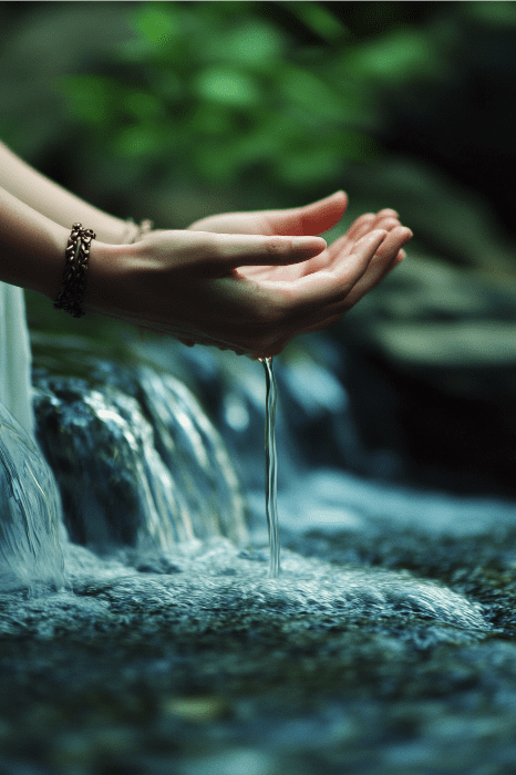 Unas manos juntas atrapan un chorro de agua sobre un fondo de exuberante vegetación y una pequeña cascada, ofreciendo un momento tan tranquilizador como una oración de AA para la ansiedad.