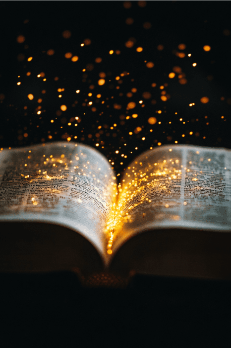 Un libro abierto con partículas doradas brillantes, como la esencia de breves devociones y oraciones diarias, que surgen de sus páginas sobre un fondo oscuro.