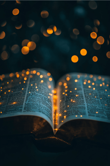 Un libro abierto con brillantes luces de hadas flota por encima, creando una atmósfera mágica que recuerda a los poemas para la iglesia en un entorno oscuro.