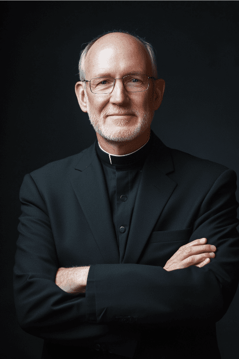 Anciano con gafas y atuendo clerical, cruzado de brazos, sonriendo afectuosamente como si acabara de compartir sabiduría sobre "Ejemplos de estatutos para iglesias", sobre un fondo oscuro.