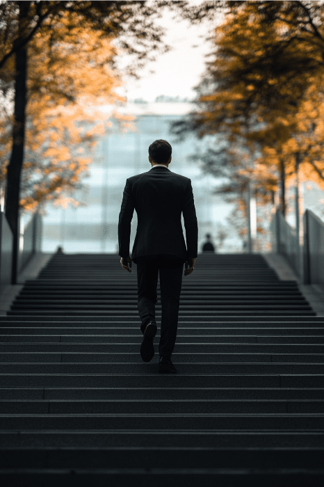 A man in a suit walks up wide stairs, framed by autumn trees and a modern building, embodying the perseverance of Jehoshaphat's tale from the Bible.