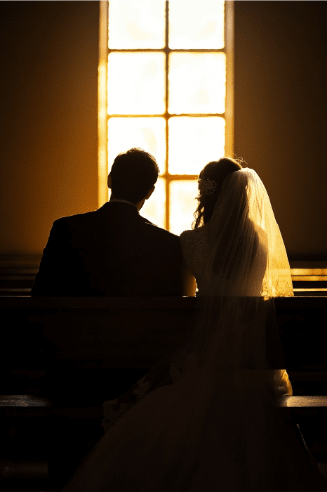 Em um momento sereno, um casal em silhueta, em trajes de casamento, senta-se junto em um banco, iluminado pela luz quente da janela, incorporando um compromisso intocado pelas consequências do adultério mencionado na Bíblia.