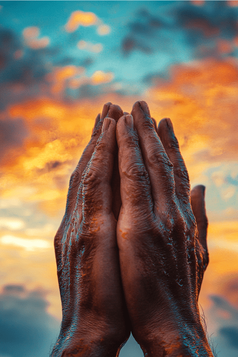 Manos juntas en un gesto de oración contra un vibrante cielo al atardecer, reminiscencia de la tranquilidad invocada por la Oración de Gratitud de AA, con las nubes sirviendo como un suave recordatorio de paz y reflexión.
