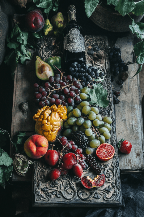 Frutas variadas y una botella de vino dispuestas en una bandeja ornamentada evocan el encanto de las ideas para tablones de anuncios de iglesias, sobre un fondo rústico de madera.