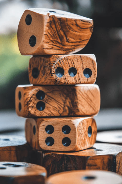 Una pila de dados de madera natural con puntos negros, dispuestos despreocupadamente sobre un fondo borroso, recuerda a los divertidos juegos que se juegan en las reuniones de la iglesia.
