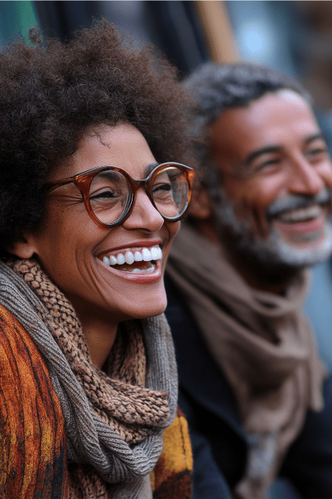 Dos personas sonrientes, con gafas y pañuelo, disfrutan de un cálido momento en un banquete de San Valentín, sobre un fondo suavemente difuminado.