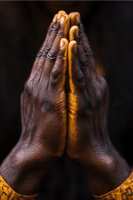 A close-up captures two hands pressed together in a prayer position, reminiscent of reflections at an Independence Day church service against a dark backdrop.