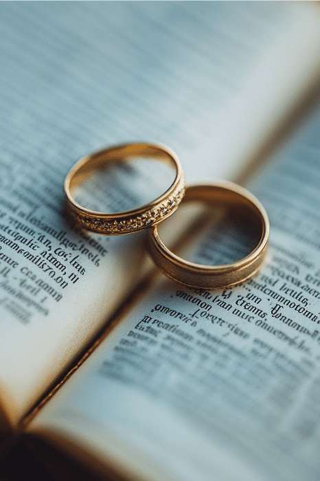 Duas alianças de ouro repousam sobre um livro aberto, sugerindo a jornada de como curar um casamento desfeito com Deus.