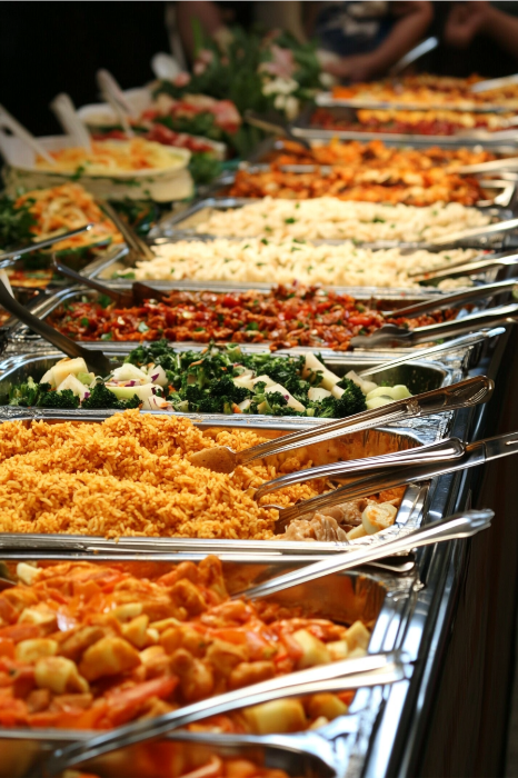 Una mesa de bufé, caprichosamente bautizada como "Devociones humorísticas para reuniones eclesiásticas", rebosa de coloridos platos -arroz, pasta y ensaladas- listos con utensilios para servir un festín divino.