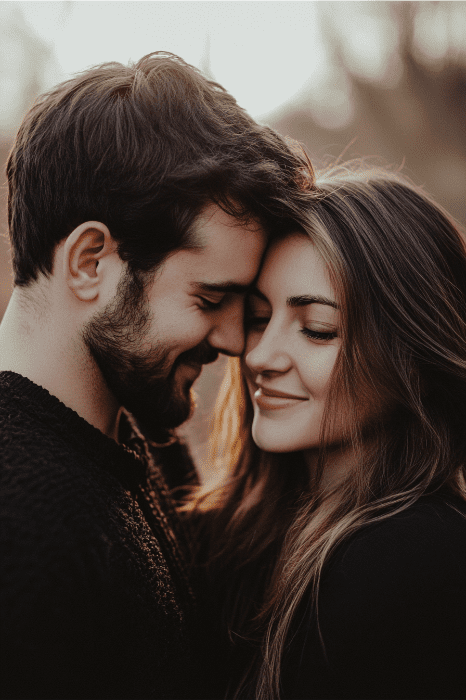 Una pareja se abraza cariñosamente, tocándose las cabezas, con un fondo de enfoque suave y una luz cálida y natural: un momento sereno que refleja el vínculo armonioso que se celebra en las escrituras atemporales.