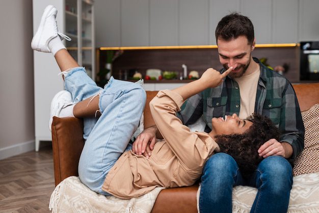 A photo of couple playing on a sofa as a depiction of what the Bible says about living together before marriage