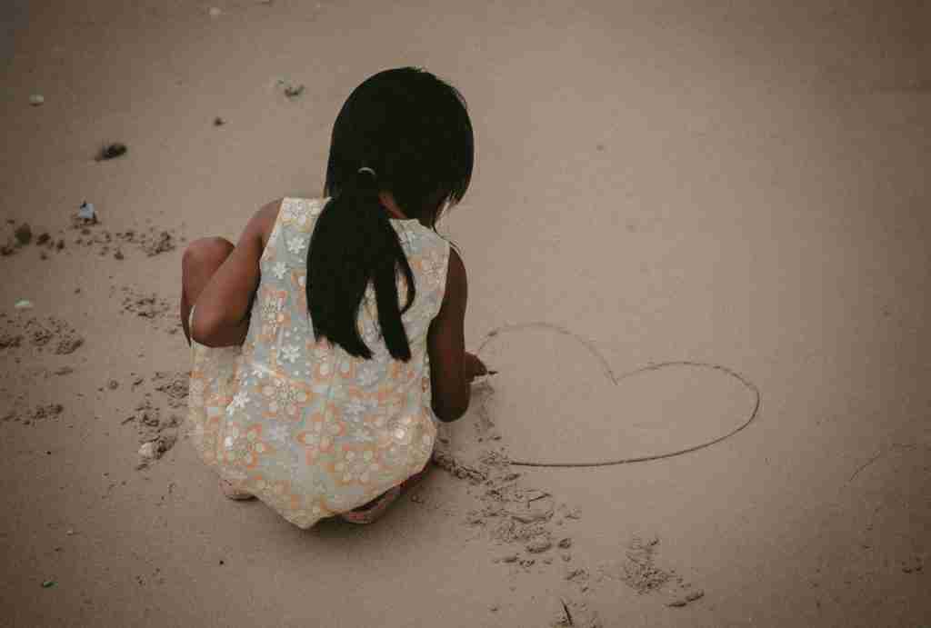 a girl drawing in sand with a stick - a unique sundays school craft for those on a budget