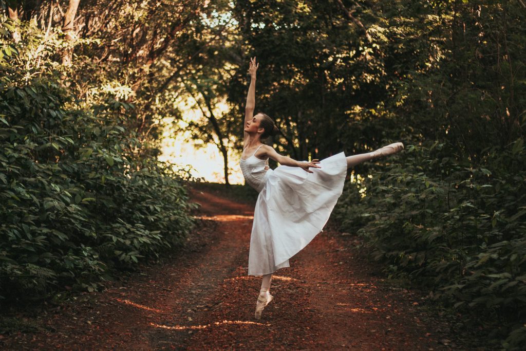 A ballerina dances on a dirt road in a forest to show dance in the Bible as worship