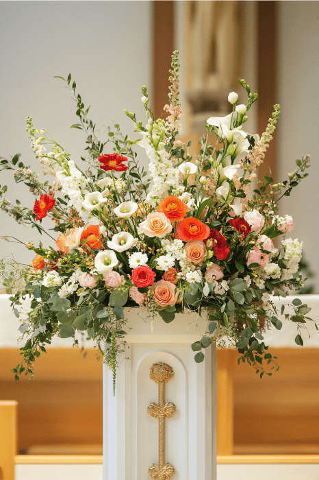 Un altar blanco adornado con un exuberante arreglo floral, que exhibe flores de colores como rosas y follaje, ofrece ideas inspiradoras para los altares de iglesia.