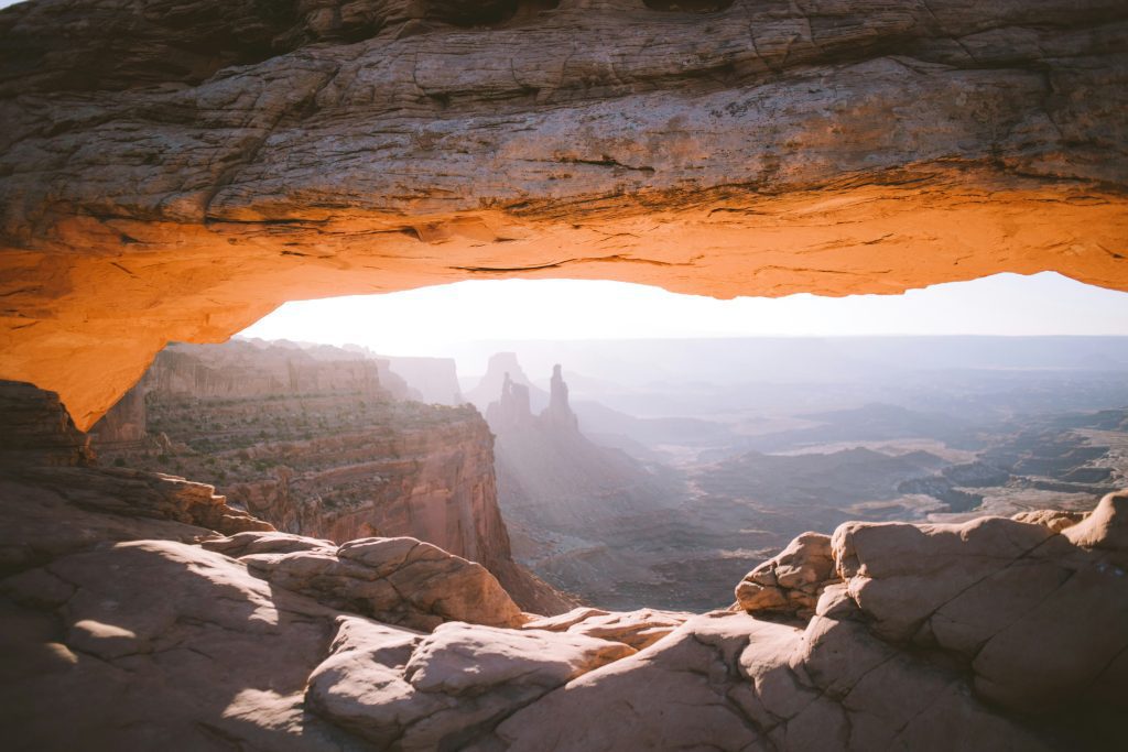 Vista del amanecer a través de un arco de roca, omnipresente en los relatos bíblicos de grandeza, que domina un vasto paisaje de cañones.