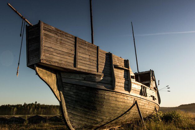 Against a vivid sunset sky, an old wooden ship rests on the grass, evoking tales of maritime adventures and perhaps even whispering stories of Noah's wife in the Bible.