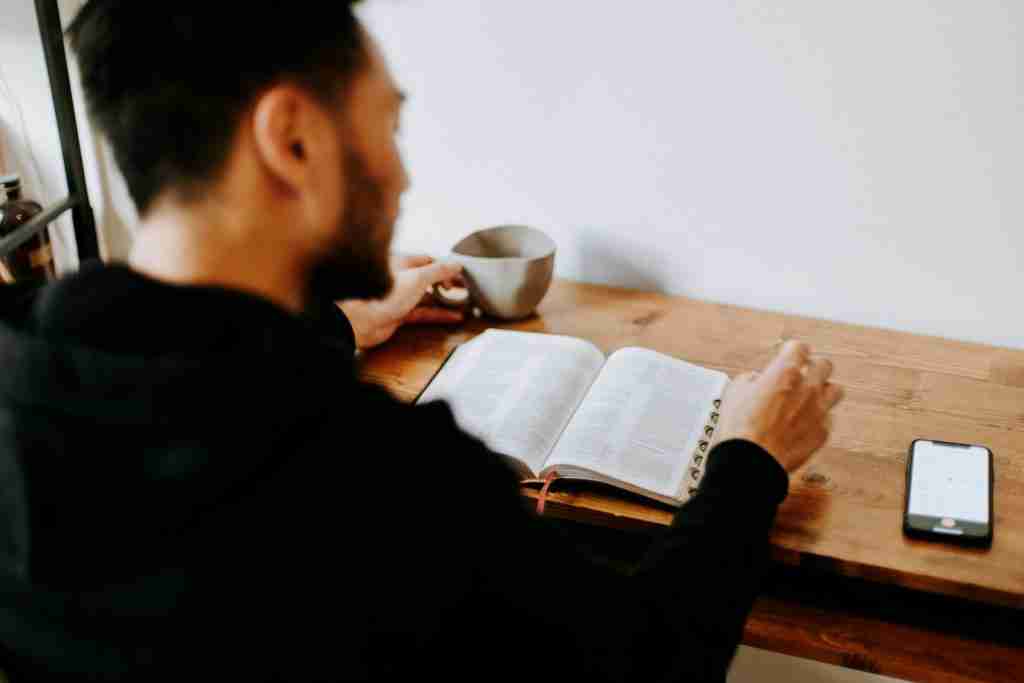 man sitting reading a bible verse to pray for church leaders