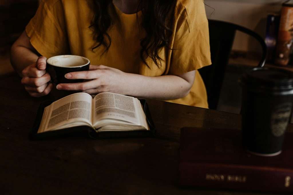 Una persona con un jersey amarillo se lleva un dedo a los labios sobre un fondo rojo, advirtiendo en silencio contra el uso de blasfemias, al igual que las eternas lecciones de la Biblia aconsejan moderación.