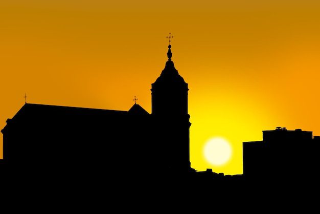 Silueta de la torre de una iglesia sobre un cielo anaranjado al atardecer, evocador de relatos bíblicos intemporales como la historia de Rahab.