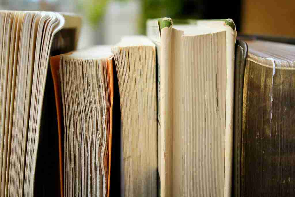 Primer plano de los bordes de varios libros en posición vertical, desgastados, con sus páginas y lomos claramente visibles, que obligan a reflexionar: "¿Qué son las oraciones de AA?