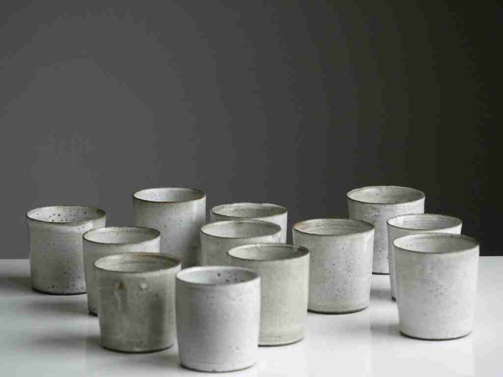¿Cuántos pasos en la oración de AA? (Alcohólicos Anónimos) Un grupo de tazas de cerámica con un diseño moteado dispuestas sobre una superficie blanca sobre un fondo gris, creando una atmósfera serena.