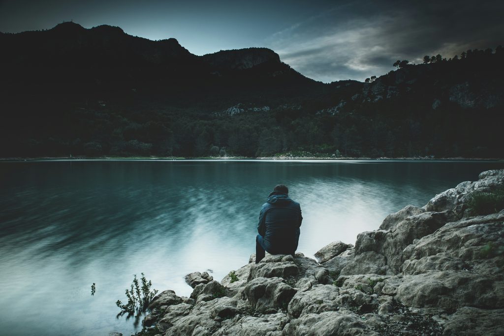 A man sits by a body of water like how Peter sat by the sea with Jesus when he had heartbreak in the Bible