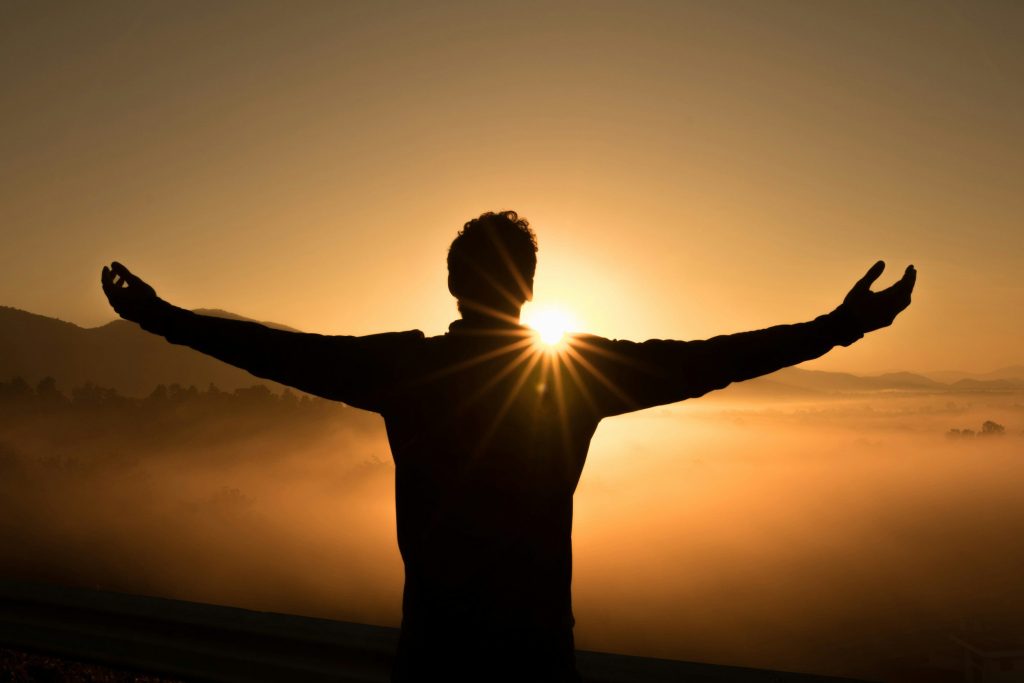 A man stretching his arms out in freedom ith the sun shining on him, like Paul's freedom from heartbreak n the Bible