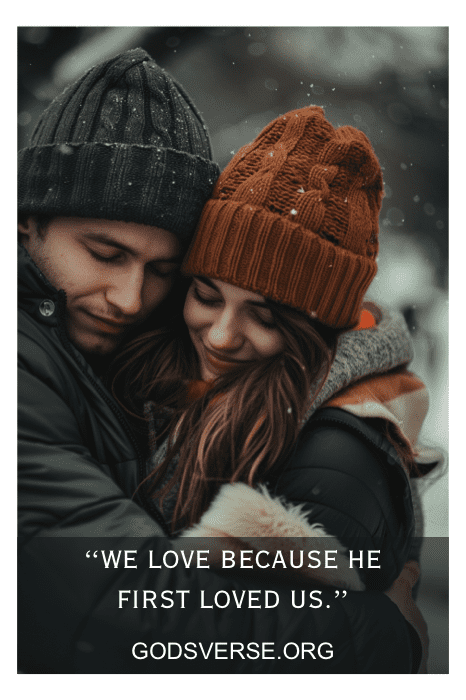Um casal vestindo roupas de inverno se abraça na neve com o texto "Nós amamos porque Ele nos amou primeiro" e "Versículo bíblico do Dia dos Namorados".