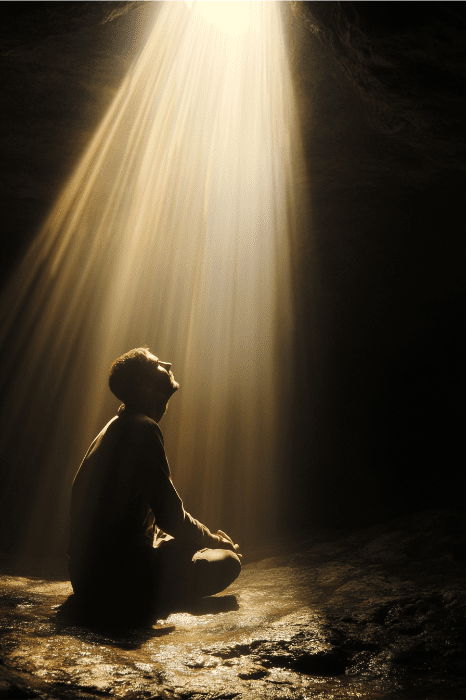 Em uma caverna escura, uma pessoa se senta banhada por um feixe de luz vindo de cima, como se estivesse encontrando consolo por meio de devoções destinadas a grupos femininos da igreja.