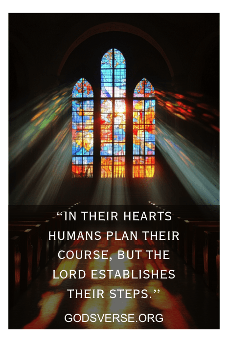 Vitral com uma citação: "Em seus corações, os humanos planejam seu curso, mas o Senhor estabelece seus passos". Escritura ideal para uma reunião do conselho da igreja, refletindo uma orientação cuidadosa e um planejamento divino.