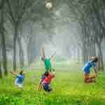 Thanksgiving Lessons for Children's Church: A Free 4-Week Plan Four children, taking a break from their thanksgiving lessons for children's church, toss a ball in the lush, green forest. They're surrounded by tall trees and soft, misty light that dances around them as they play.