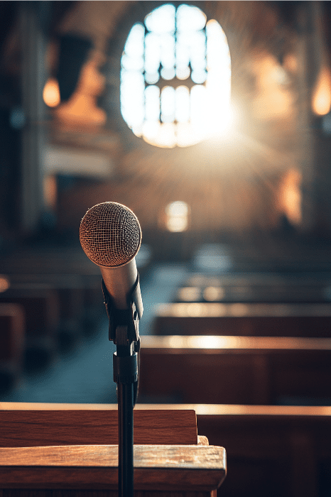 In the empty church, a microphone stands on a podium, ready for the expository sermon series. Sunlight streams through a stained glass window, casting colorful patterns across the floor.