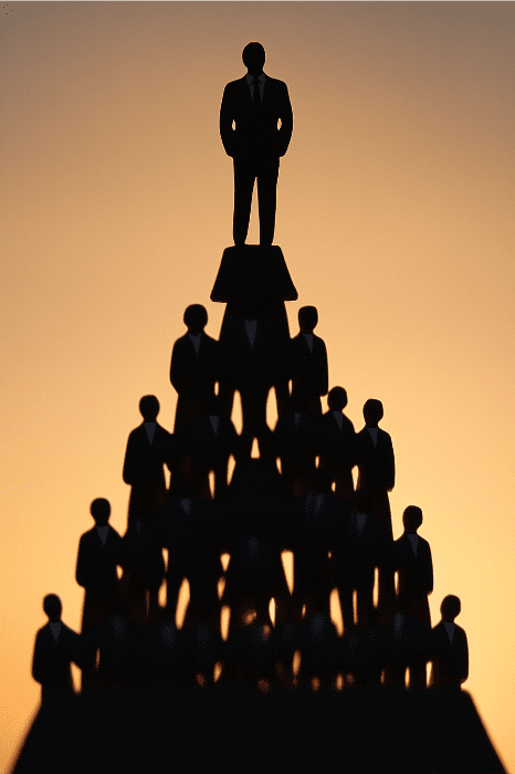 Silhouette of a pyramid of people in suits, one person triumphantly at the top, against an orange gradient background—a metaphor perhaps for the valid reasons for changing churches or seeking new spiritual horizons.