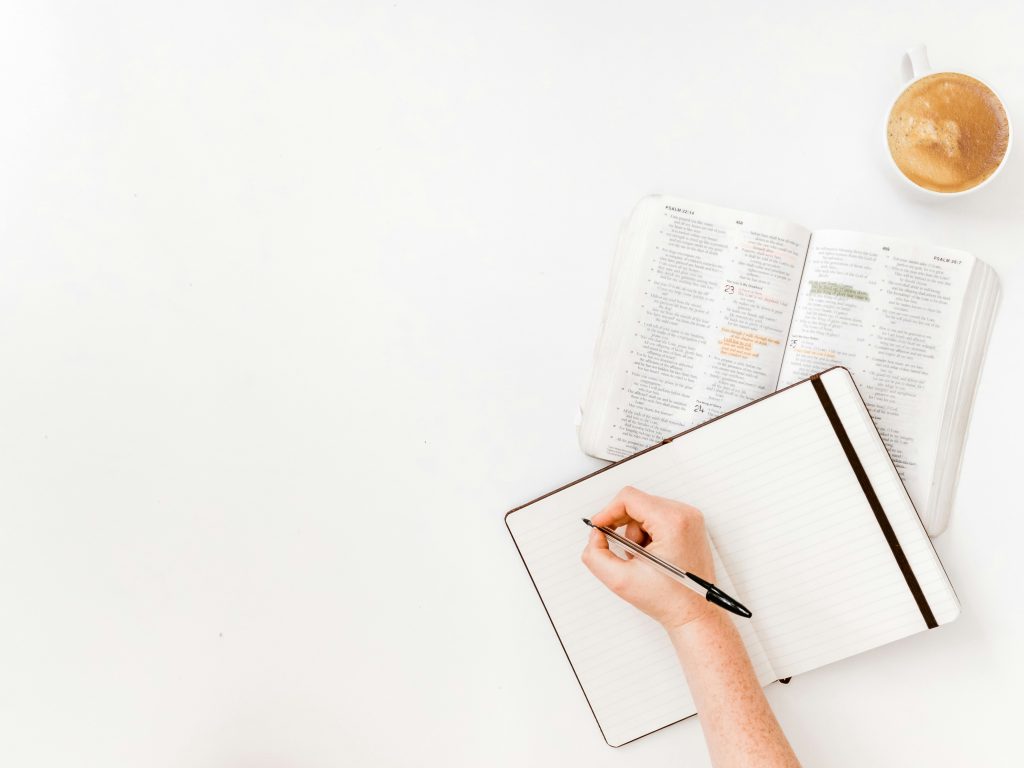 a person studies how many chapters there are in the bible with a notebook, pen, and coffee next to their bible