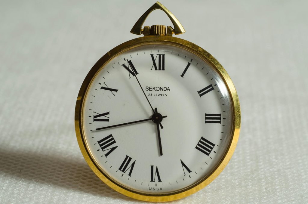 This gold-rimmed Sekonda pocket watch, reminiscent of ancient tales, boasts Roman numerals and the inscription "23 jewels USSR" on its textured surface, echoing the timeless nature of stories like Esau and Jacob's in the Bible.