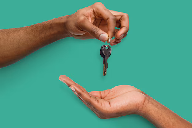 One hand passes a key to another open hand against a solid green background, symbolizing trust and new beginnings—echoing the meaning of 222 in the Bible as a sign of balance and divine guidance.