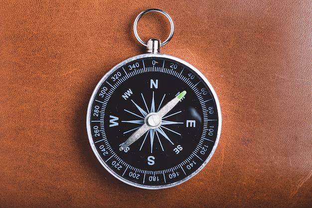 A black compass with metal casing rests on a brown leather surface, evoking the sense of guidance and meaning—much like what does the number 4 mean in the Bible, symbolizing creation and stability.