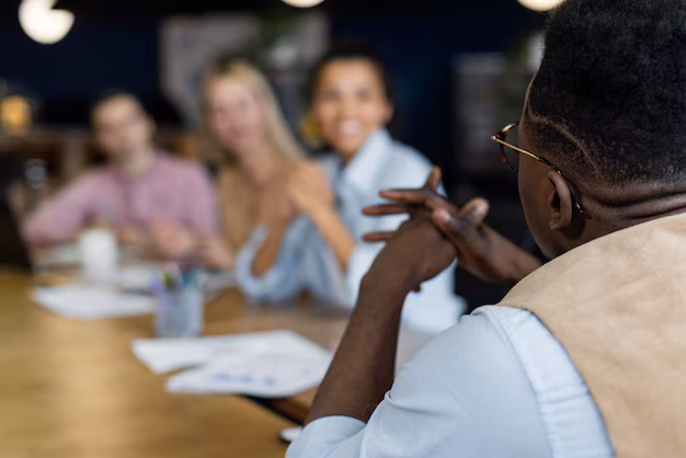 A black man talking to others across a table