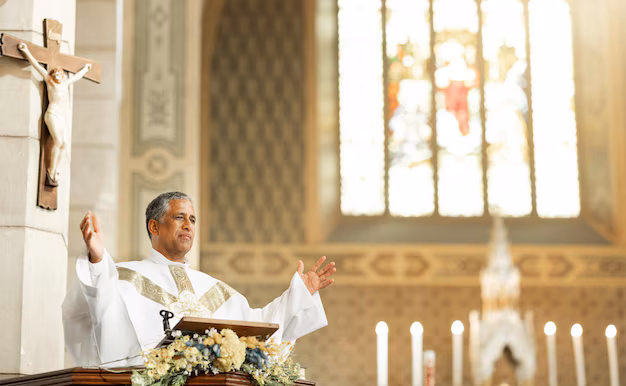 A priest in white robes speaks at a church altar with candles and a crucifix, perhaps reflecting on teachings such as "What are the 73 Books in the Bible?.