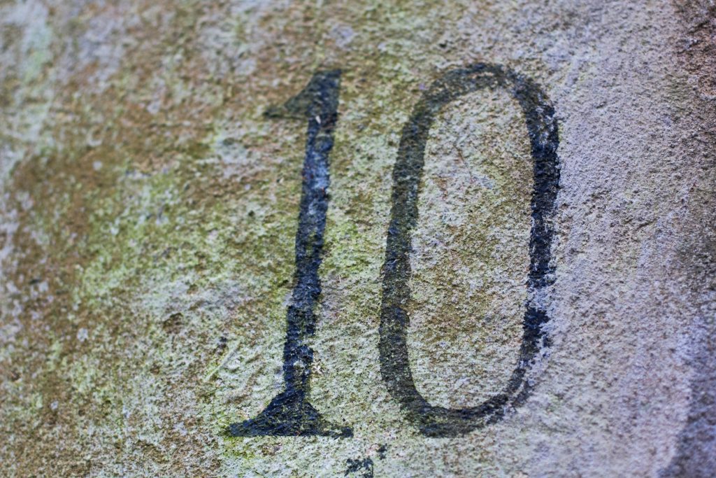 O número 10, que muitas vezes simboliza a ordem divina na Bíblia, está pintado de preto em uma superfície de pedra desgastada e coberta de musgo.