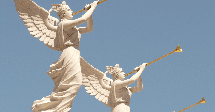 Two white winged angel statues blowing golden trumpets against a clear blue sky.