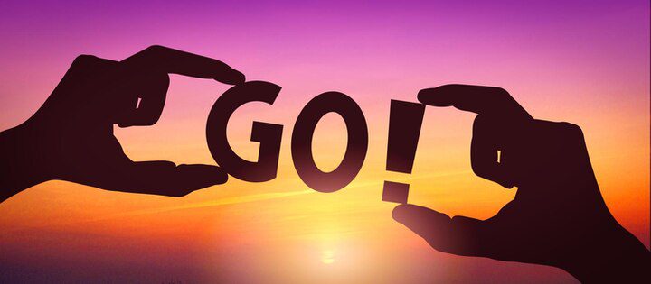 Silhouetted hands hold letters spelling "GO!" against a colorful sunset sky, echoing the call in the Bible about missions to share hope with the world.