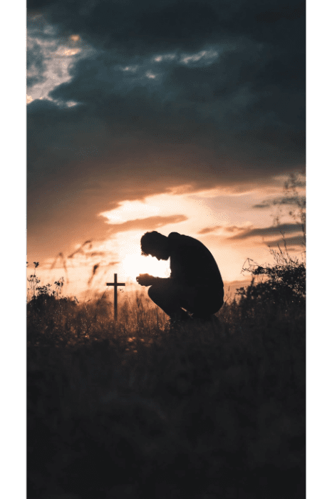 Silueta de una persona arrodillada junto a una cruz al atardecer, con dramáticas nubes en el cielo, encarnando la esencia de las oraciones de perdón descritas en la Biblia.