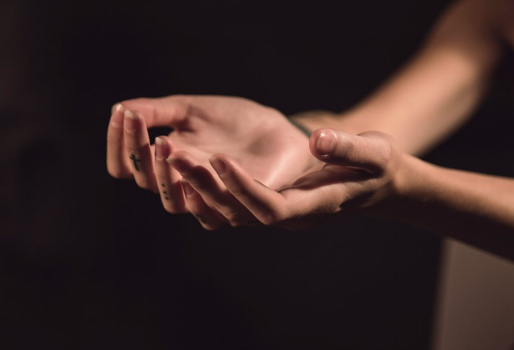 Close-up of a pair of open hands facing upward, fingers slightly curved against a dark background, perhaps seeking guidance or revelation—much like pondering what the number 10 means in the Bible.